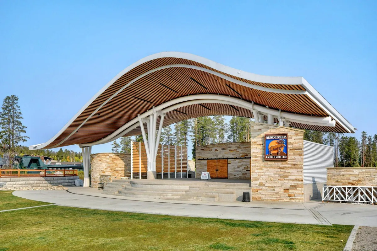 The striking exterior of an event center with a curved roof and stone façade, clearly marked by event signage. The image evokes anticipation for concerts and outdoor community gatherings, capturing the energy and excitement of local festivals or performances.