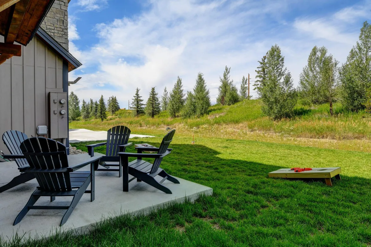 A welcoming backyard or lawn area set up for friendly cornhole games, with Adirondack chairs and a green outdoor space. The atmosphere is relaxed and inviting, ideal for family gatherings and outdoor play.