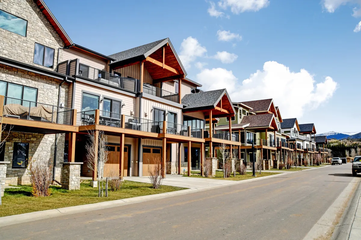 This exterior image showcases a row of modern homes, each with balconies, large windows, and beautifully landscaped front yards. The inviting scene captures a sense of community while illustrating the upscale, resort-style environment.