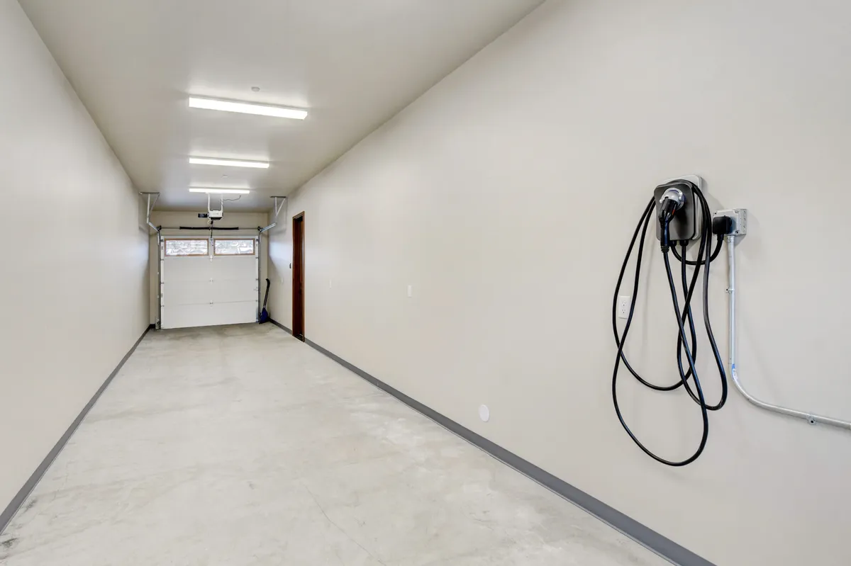 A spacious, clean garage with a visible garage door, utility connections, and ample wall space, ideal for storing sports equipment, bikes, or outdoor gear. The uncluttered area provides a sense of readiness for adventure and supports practical needs for visitors with multiple activities planned.