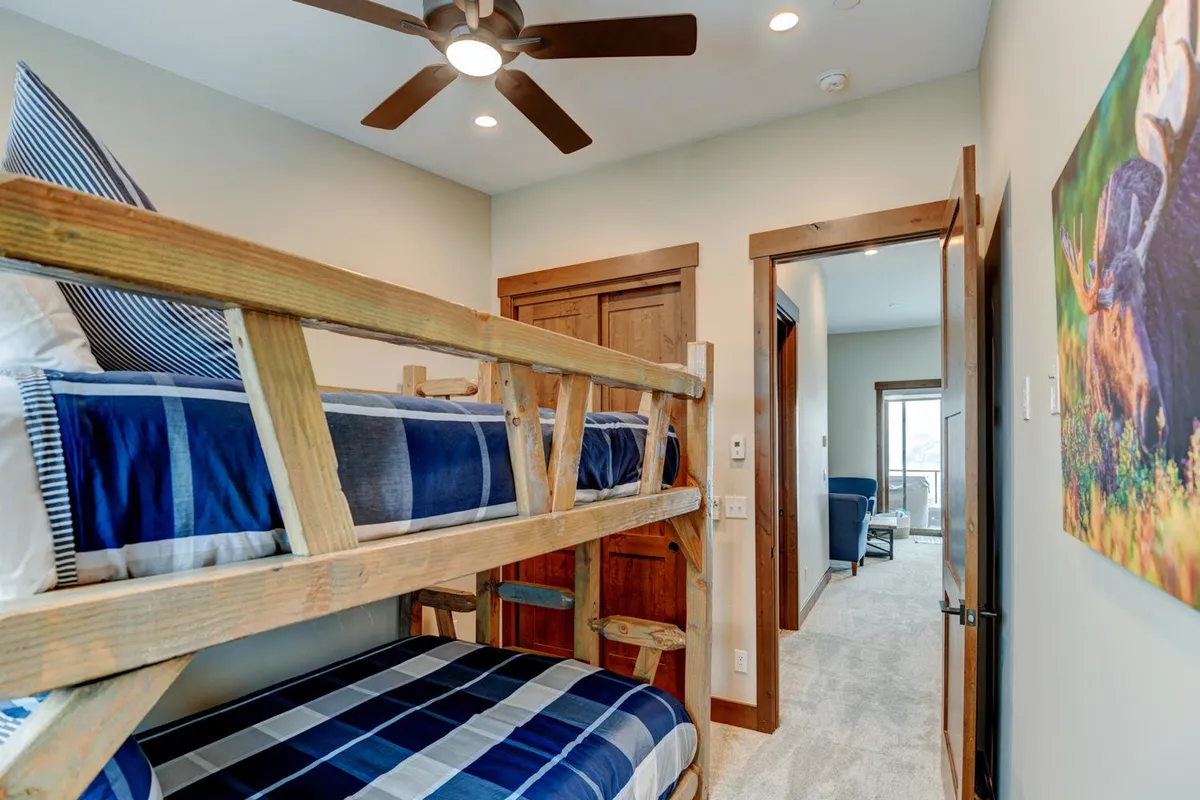 A playful bunk room with a sturdy bunk bed, wooden details, and textured wall art, creating a cozy and fun environment ideal for children or families. The inviting setup encourages memorable sleepovers and family gatherings.