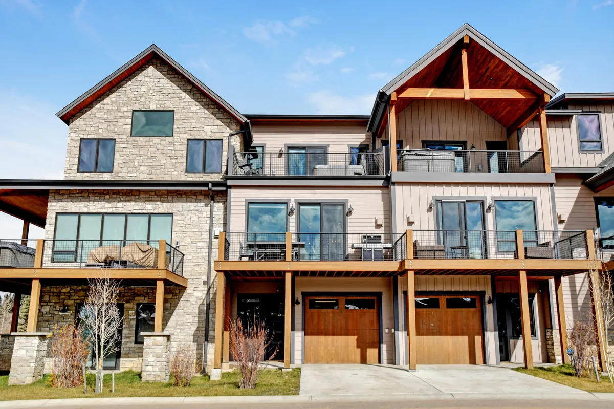 The image showcases the striking exterior of a luxury mountain villa in Fraser, Colorado, featuring a stone facade, warm wooden accents, expansive windows, and spacious balconies perfect for outdoor relaxation or gatherings. The inviting outdoor spaces are designed for enjoying sunsets, barbecues, and making memories with friends and family.