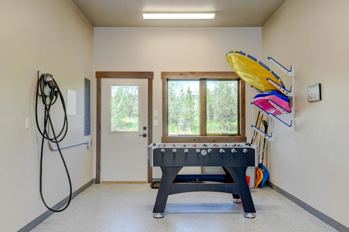 A recreational room with a foosball table, large windows, and colorful kayaks, blending playful indoor recreation with hints at outdoor activities. The space is designed for socializing, planning trips, and gearing up for the next adventure, illuminated by natural light.